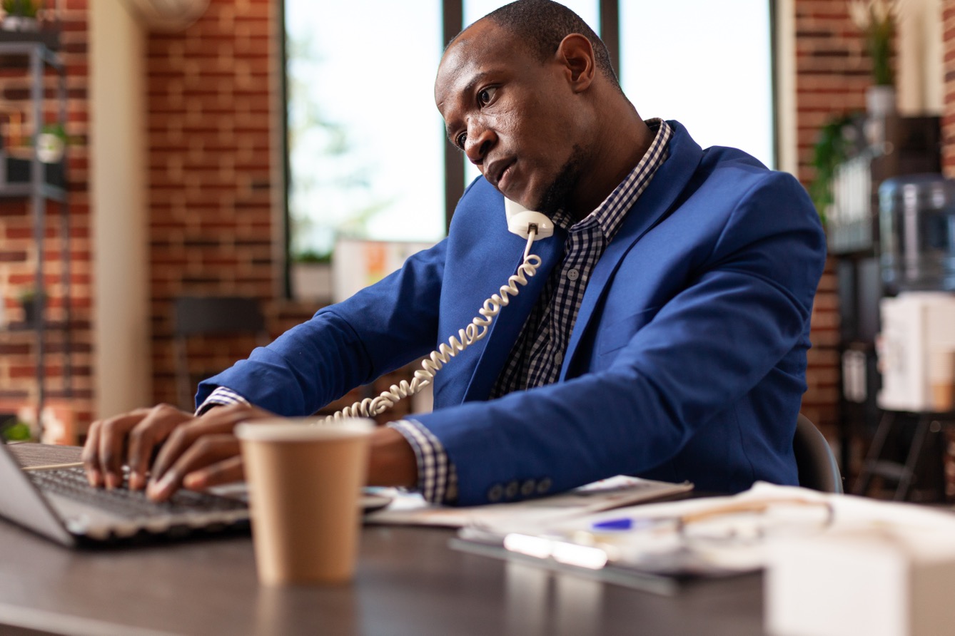 man working on laptop phone